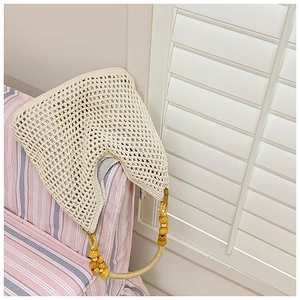 Detail of crochet straw beach bag with wooden bead handle and openwork knit pattern