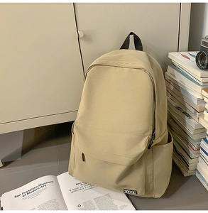 Minimalist beige campus backpack featuring front zipper pocket and side water bottle pockets