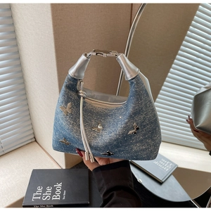 Détails d'un sac à main en denim bleu avec papillons métalliques et poignée argentée