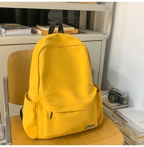 Detail of a bright yellow nylon school backpack on a wooden chair with vintage accessories