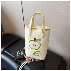 Detail shot of the cream-colored PU leather bag with green apple embroidery and strap