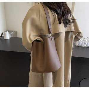 Detail of brown lychee grain leather bucket bag showing texture and wide shoulder strap