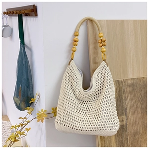 Detail of hand-woven off-white hollow mesh tote bag with decorative wood bead handles