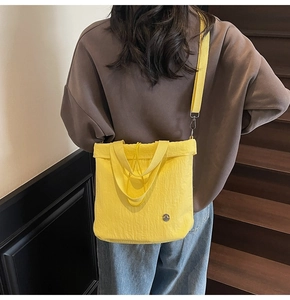 Detail of vibrant yellow crossbody bucket bag showing nylon texture and versatile straps