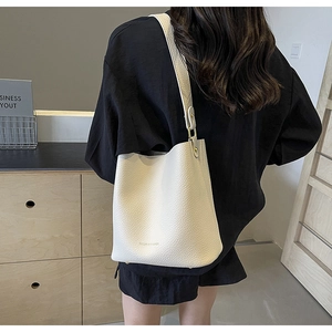 Detail of creamy white pebble leather bucket bag with embossed logo and elegant pleats