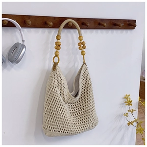 Detail of beige crochet tote bag featuring wooden bead handles and hollow mesh texture