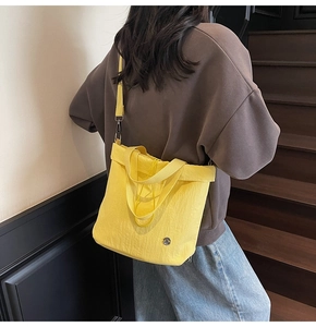 Lemon yellow pleated tote bag shown worn as a crossbody style on a female model
