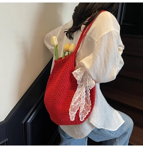 Texture détaillée du sac fourre-tout en tricot rouge avec un nœud en dentelle blanche