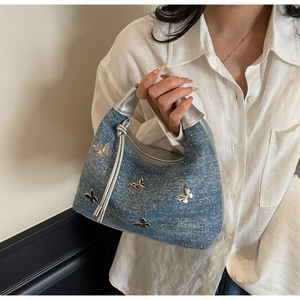 Détail d'un sac à main en jean bleu avec papillons argentés et finition pailletée