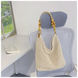 Detail view of beige handmade crochet beach bag with decorative wooden beads on strap
