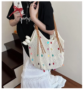 Détail d'un sac cabas en tricot blanc orné de paillettes colorées et anses en cuir