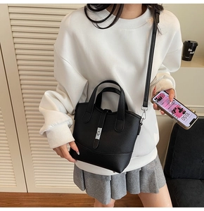 Close-up of black lychee-grain leather tote bag with silver buckle and crossbody strap