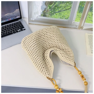 Detail of beige crochet straw tote bag featuring decorative wooden bead handles