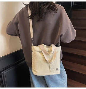 Detail showing cream drawstring bucket bag with sturdy fabric handles and small metal logo