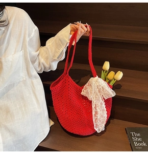 Détail du cabas en crochet rouge avec nœud en dentelle blanche et texture tressée