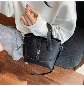 Detail of black litchi grain leather tote with silver metal lock and comfortable handles