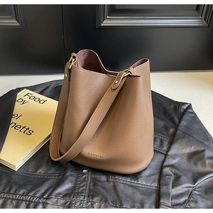 Detail of brown lychee grain leather bucket bag with embossed logo on black leather background