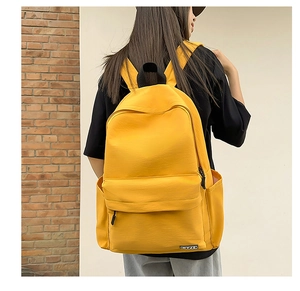 Detail of a bright yellow canvas backpack featuring side pockets and a brand label