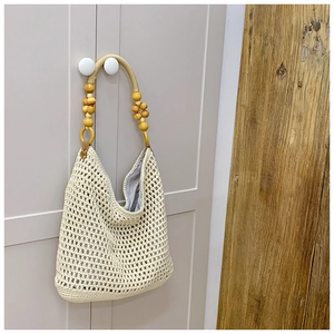 Detailed close-up of woven tote bag featuring decorative wooden beads on the handle