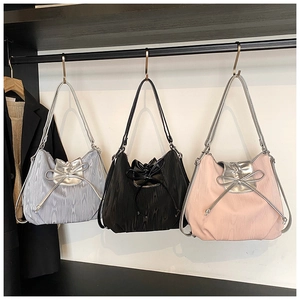Close-up of pleated metallic tote bags in silver, black and pink with bow drawstrings