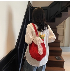 Détail du sac cabas rouge crocheté à la main avec grand nœud en dentelle blanche et tulipe