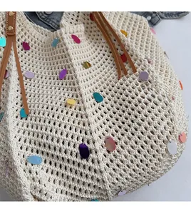 Close-up of knit tote bag featuring colorful sequins and brown faux leather handle