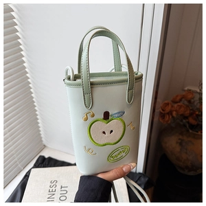 Detailed close-up of mint green leather apple handbag with embroidery and shoulder strap