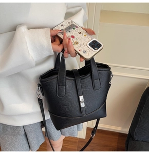 Detail of black lychee grain leather bucket bag with silver metal twist lock and dual handles