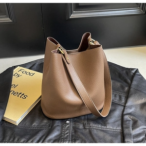 Detail of brown litchi pattern leather bucket bag with gold hardware and shoulder strap