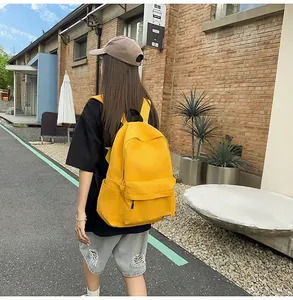 Outdoor shot of a bright yellow canvas backpack showing size and capacity on a model