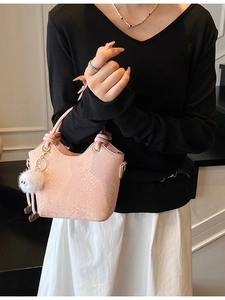 Sac seau rose à motif serpent avec poignée nouée et breloque, porté par un mannequin
