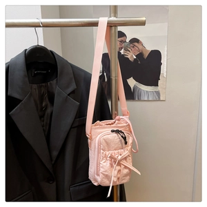 Detailed view of pink drawstring nylon bag with a bow knot on a display stand