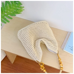 Detail showing handwoven hollow crochet pattern and wooden bead accents on straw bag