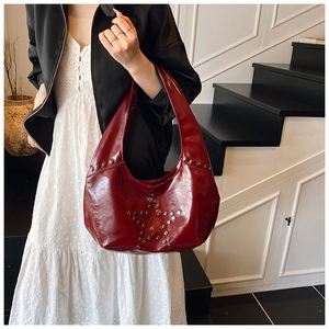 Close-up of a burgundy vintage leather shoulder bag with silver star rivet studs