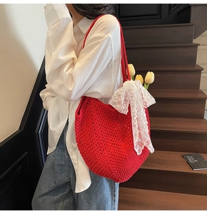 Détail du sac cabas au crochet rouge avec nœud en dentelle blanche sur un mannequin