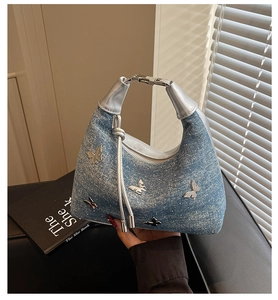 Detail of light blue glitter denim handbag with 3D silver metal butterflies and tassel