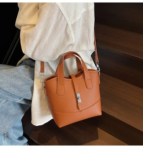 Borsa a secchiello marrone in pelle con chiusura argento e tracolla sulle scale
