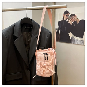 Detailed view of pink mini crossbody bag featuring a bow design and drawstring closure