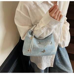 Détail du sac en jean bleu clair avec papillons argentés 3D et poignée à cordon chic