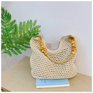 Detail of woven mesh beach tote bag featuring circular wooden bead handle and cotton lining