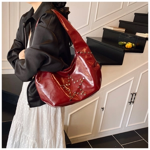 Model wearing a dark red patent leather hobo bag with star-shaped metal rivets