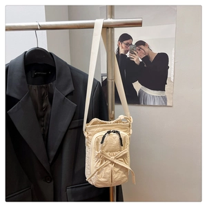 Detail of beige nylon crossbody bag with drawstring closure and bow decoration