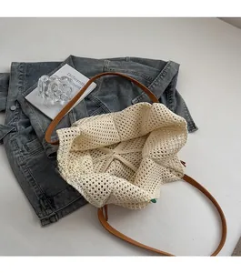 Top-down view of cream crochet tote bag with brown leather handles and hollow knit pattern