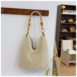 Detail of hand-woven mesh tote with wooden beads handles on a minimalist hanger