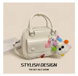 Macro view of cream faux leather handbag with plush monster charm and shiny finish