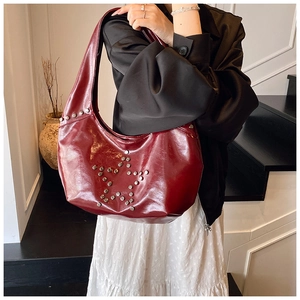 Detail of dark red crescent bag with silver star-shaped rivets on glossy leather