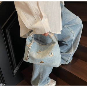 Close-up of denim handbag with silver butterfly accents and rhinestone details