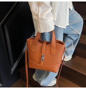 Close-up of orange lychee leather bucket bag with silver metal buckle on stairs