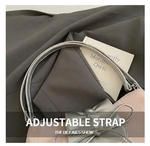 Close-up of adjustable silver strap and metallic bow detail on a pink leather tote bag