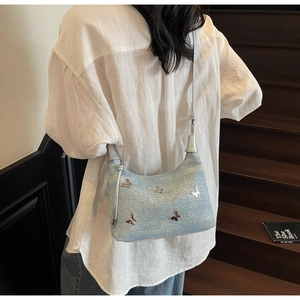 Gros plan d'un sac à sequins bleu clair avec papillons argentés porté par un modèle